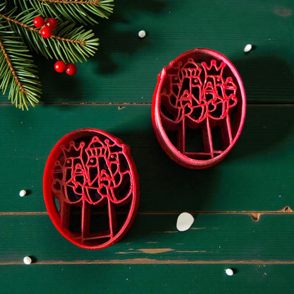 Two red Three Kings cutters on green background with pine branches