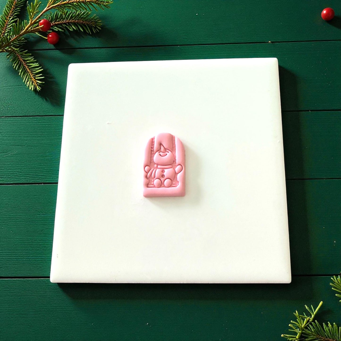 Small pink snowman swing clay imprint centered on white tile