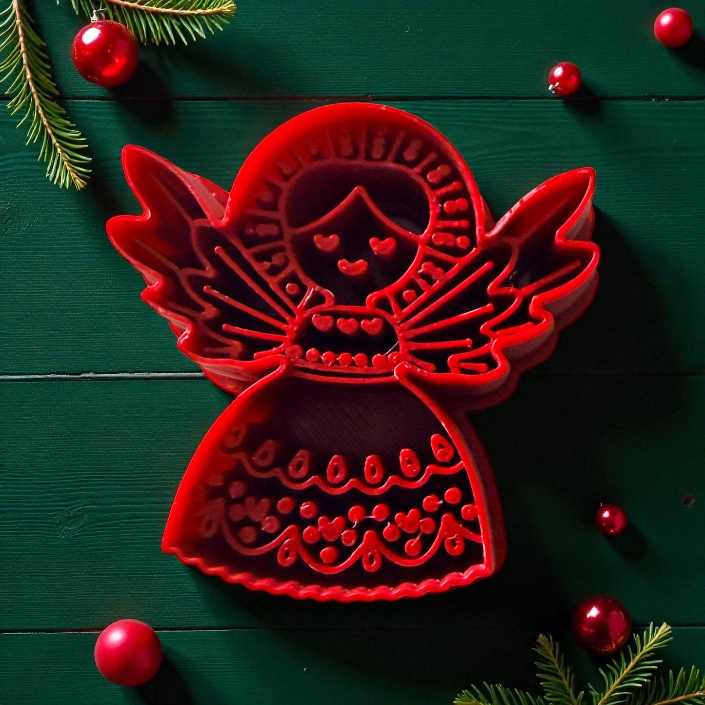 Red folk angel polymer clay cutter with wings and intricate details on green background