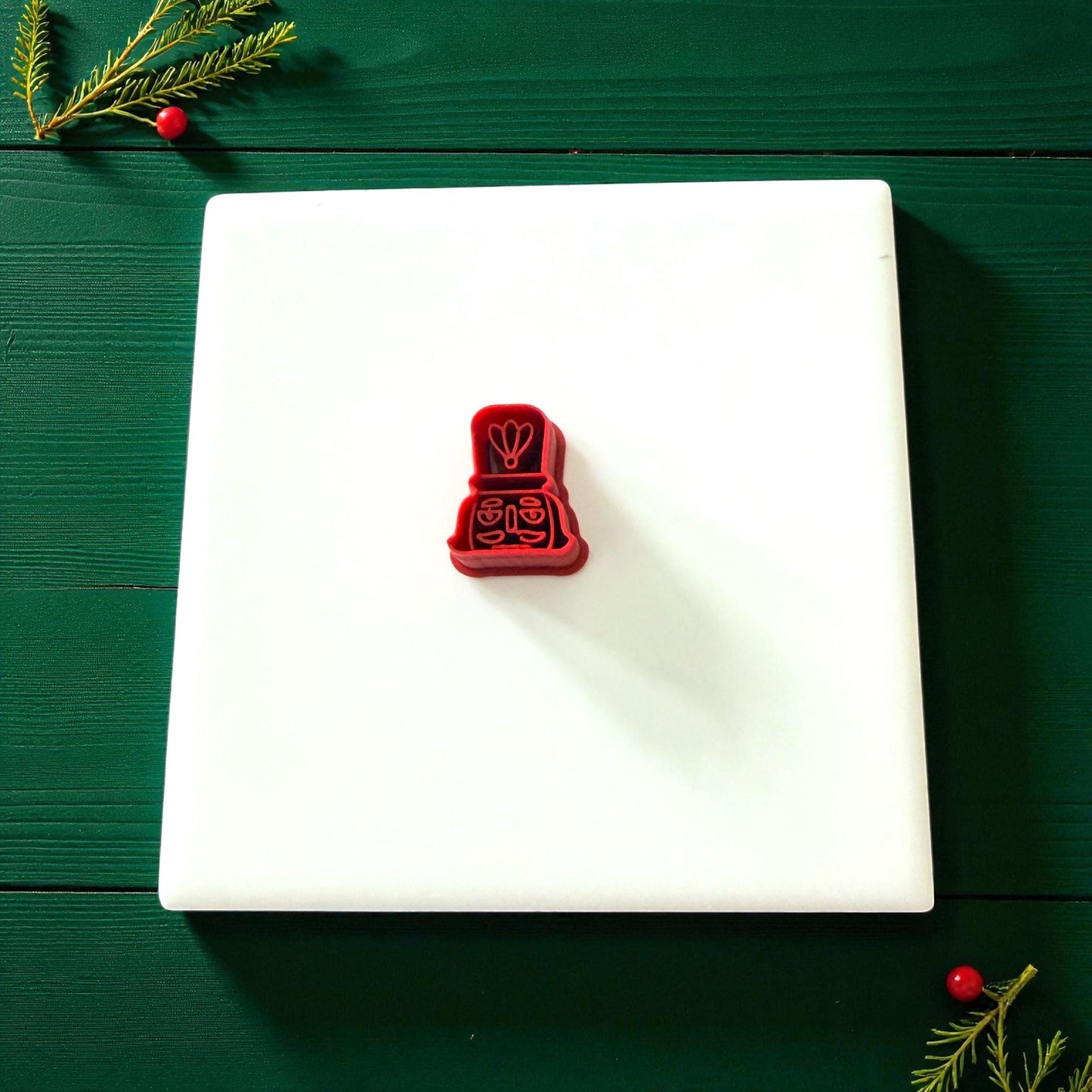 Red nutcracker cutter centered on white tile with green background