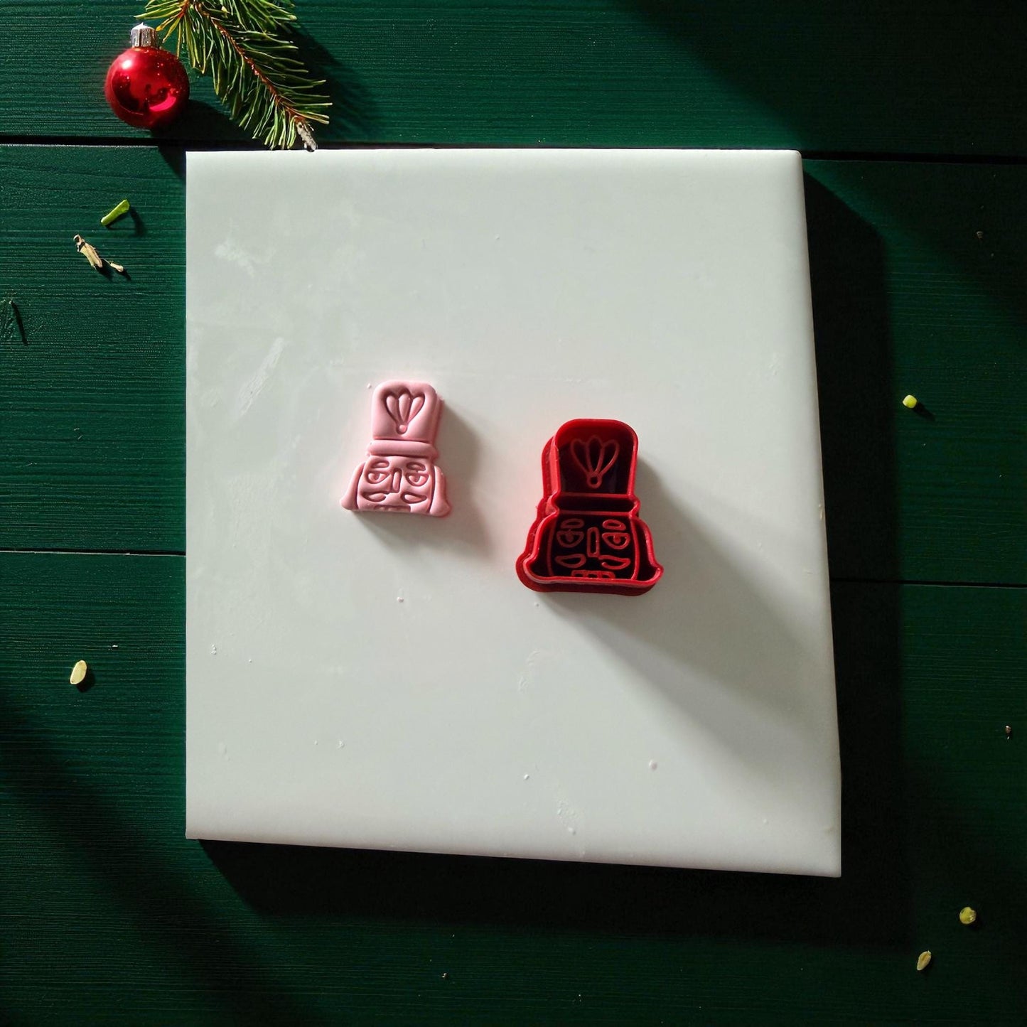 Pink and red nutcracker cutters side by side on white tile
