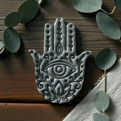 Close-up of gray Hamsa clay imprint showing eye and floral pattern