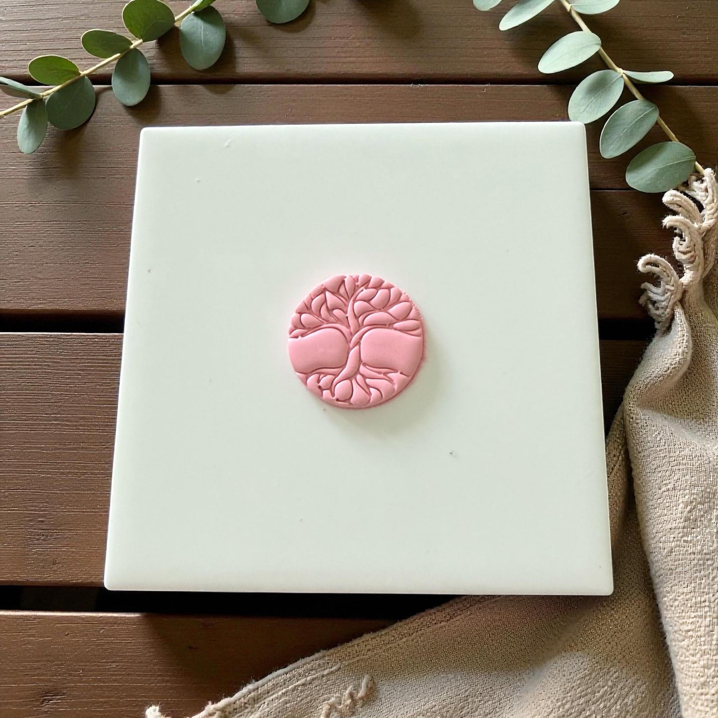 Pink tree of life clay piece centered on white tile with neutral tones