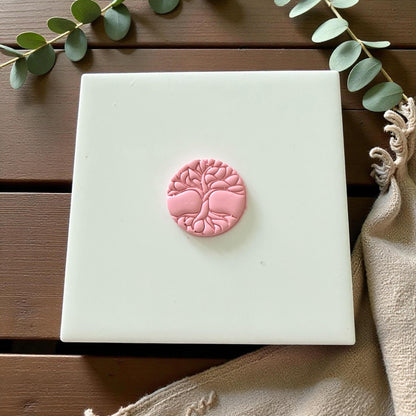 Pink tree of life clay piece centered on white tile with neutral tones