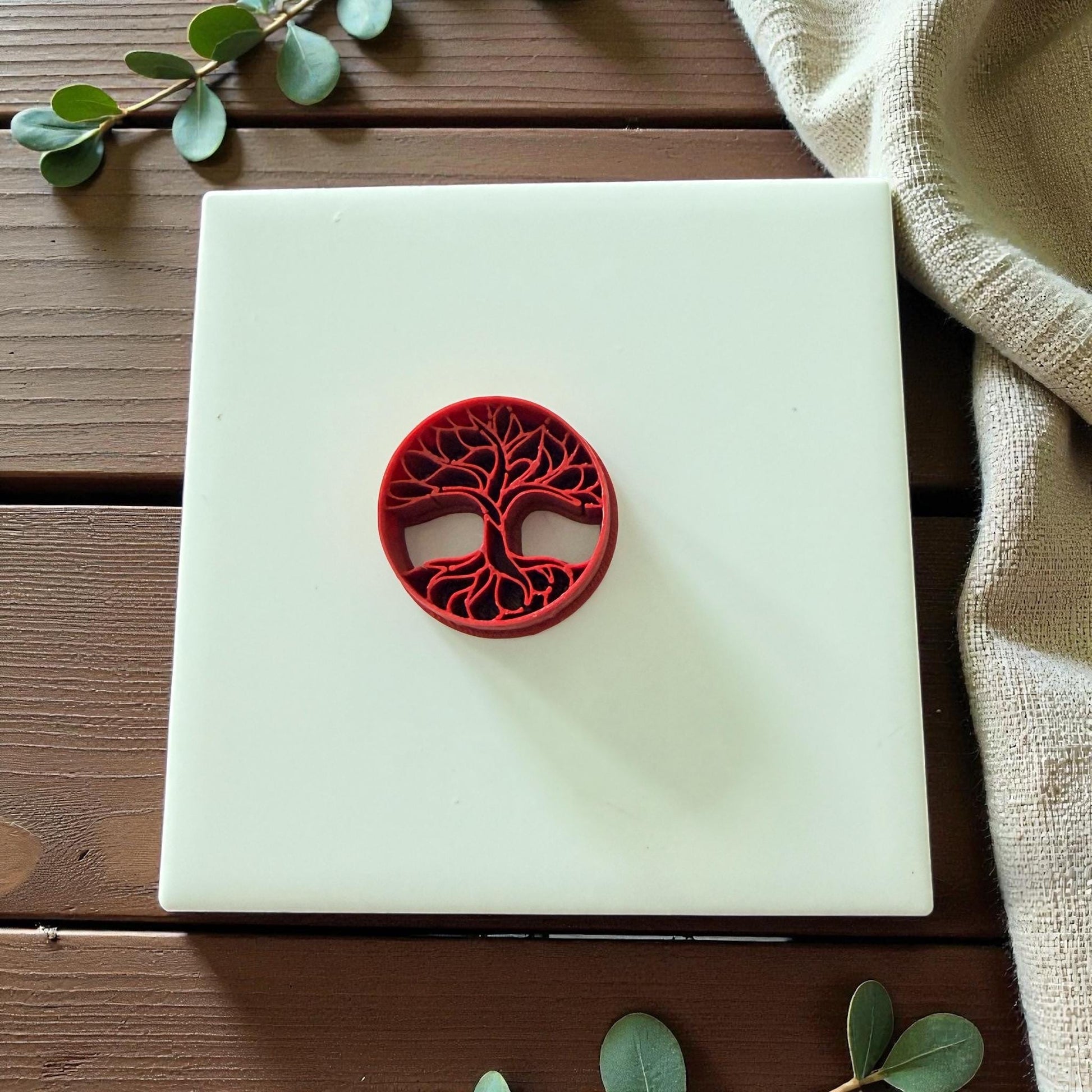 Round tree of life clay cutter displayed on white tile with soft lighting