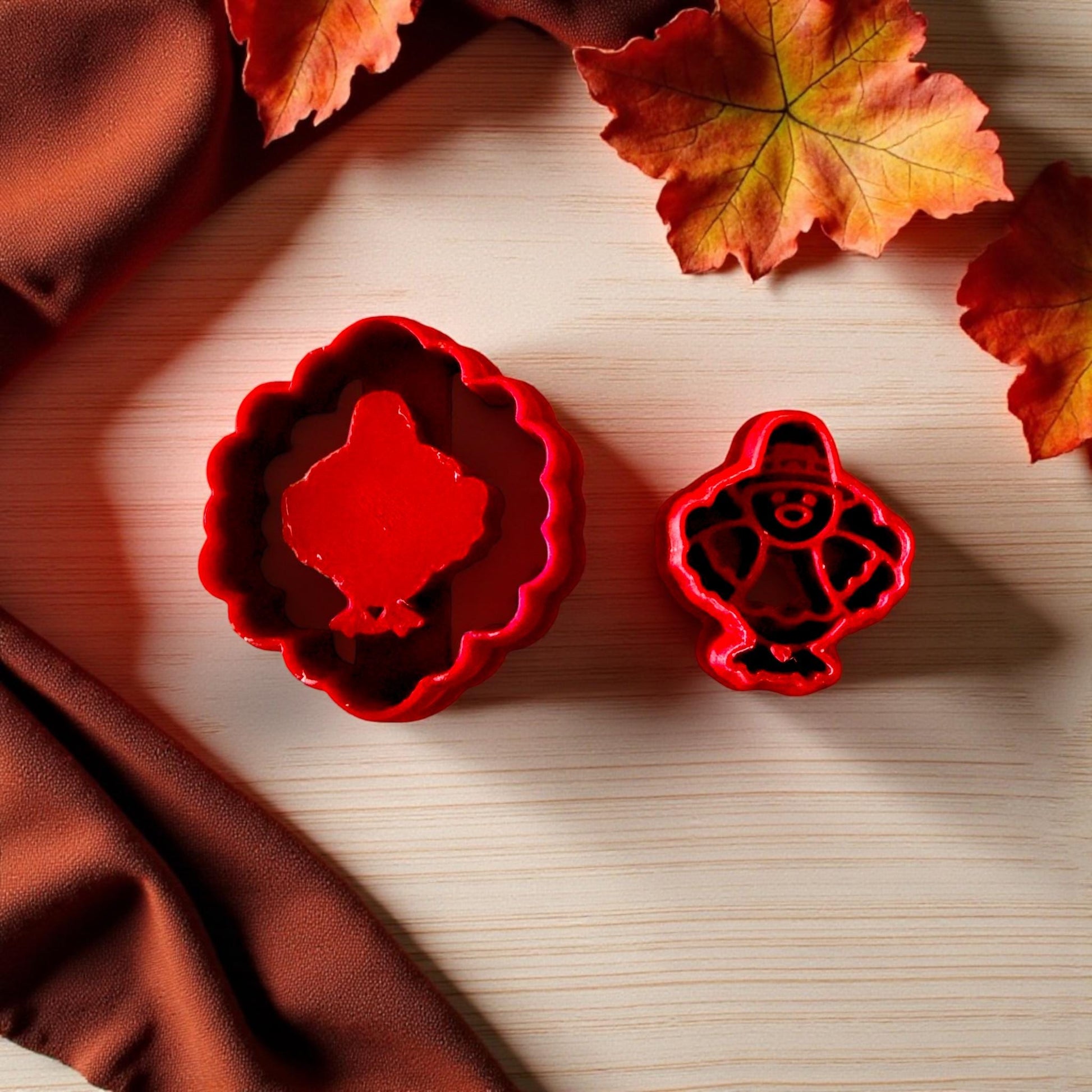 Close-up of red pilgrim turkey and scalloped cutters on light wood with fall leaves