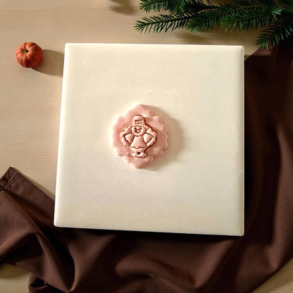 Pilgrim turkey clay imprint centered on white tile with pumpkin and greenery