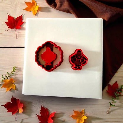 Red turkey and scalloped cutters on white tile surrounded by autumn leaves