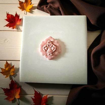 Pilgrim turkey clay imprint centered on white tile with pumpkin and greenery