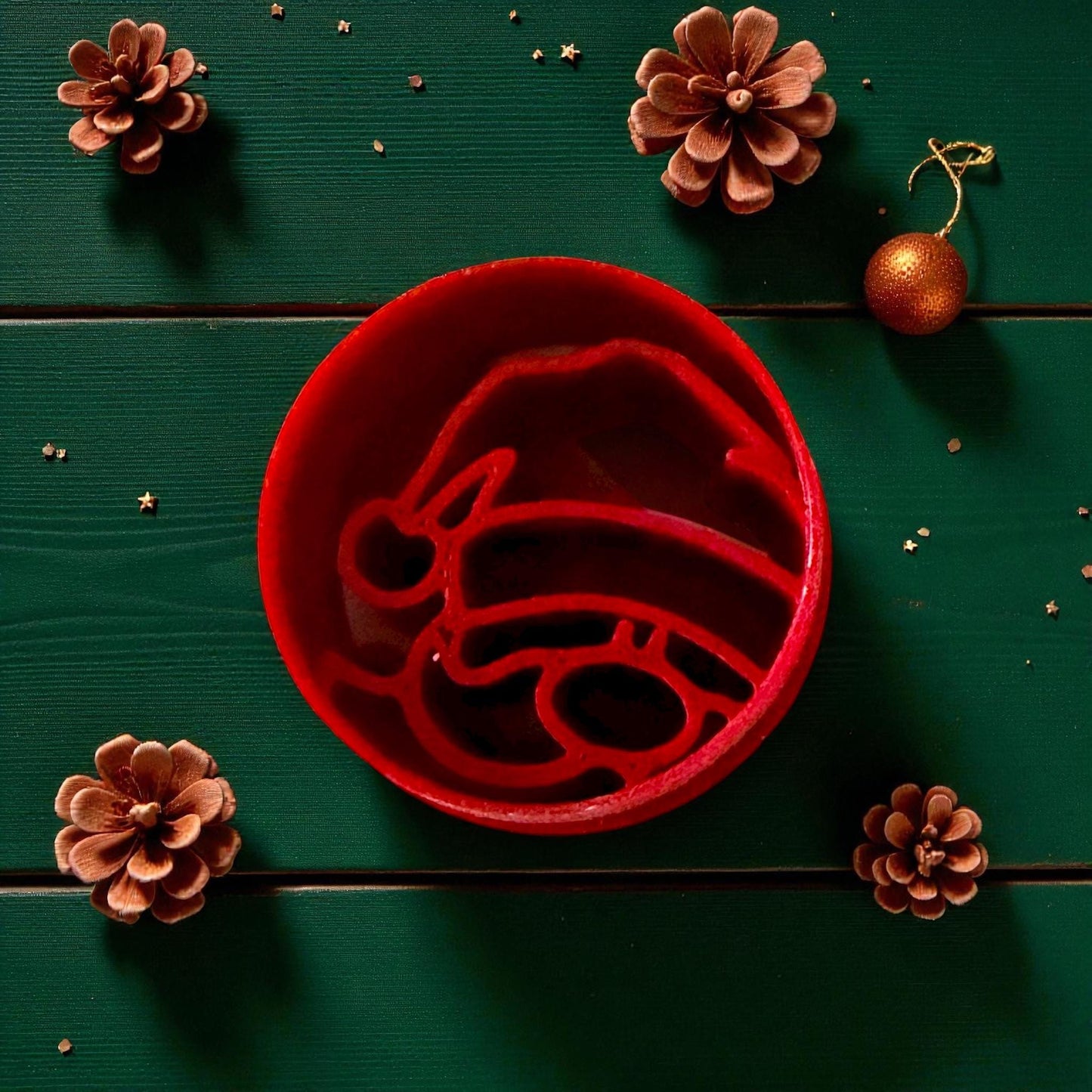 Close-up of red Santa cutter surrounded by pinecones and gold ornaments
