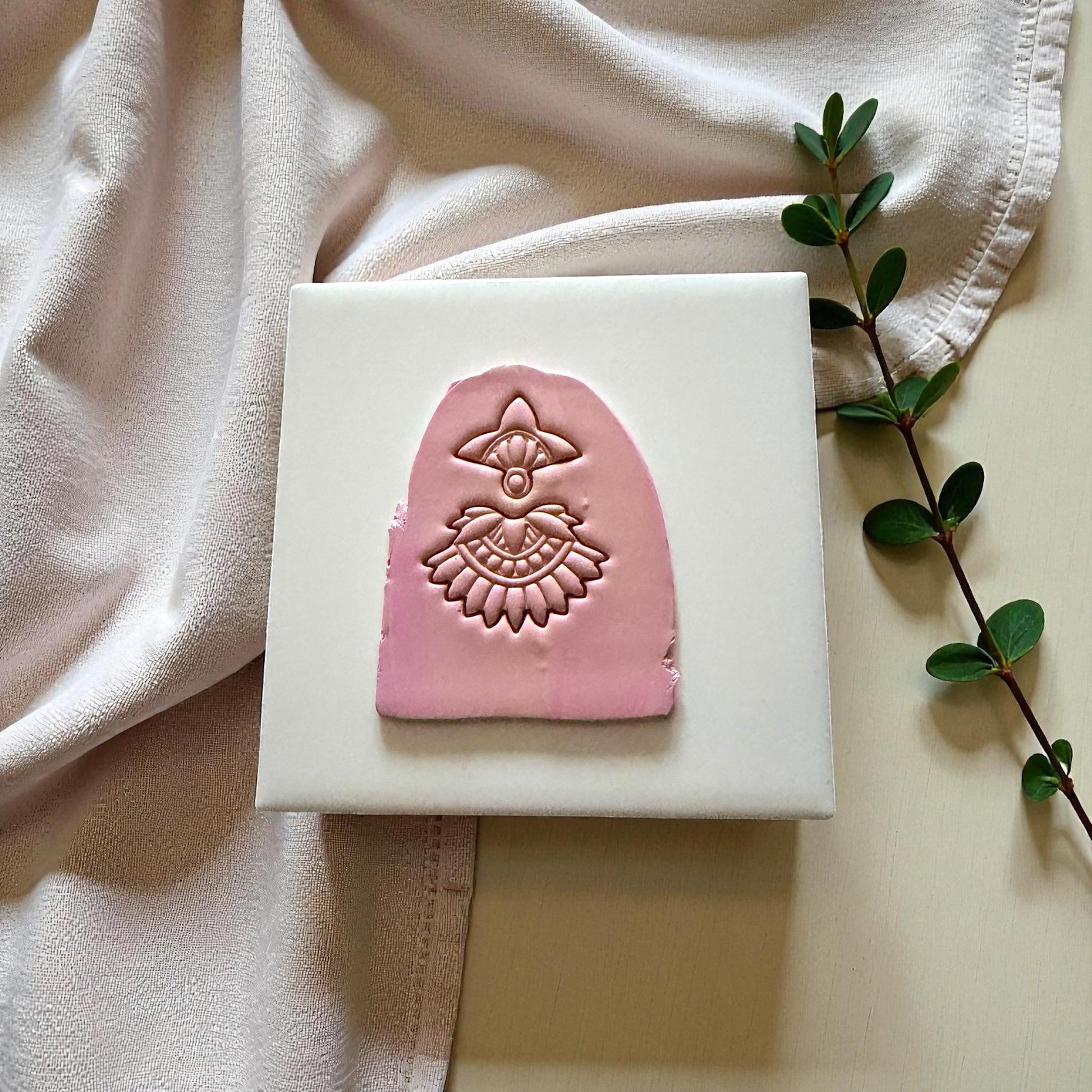 Boho fan clay imprint on pink clay sheet over neutral fabric