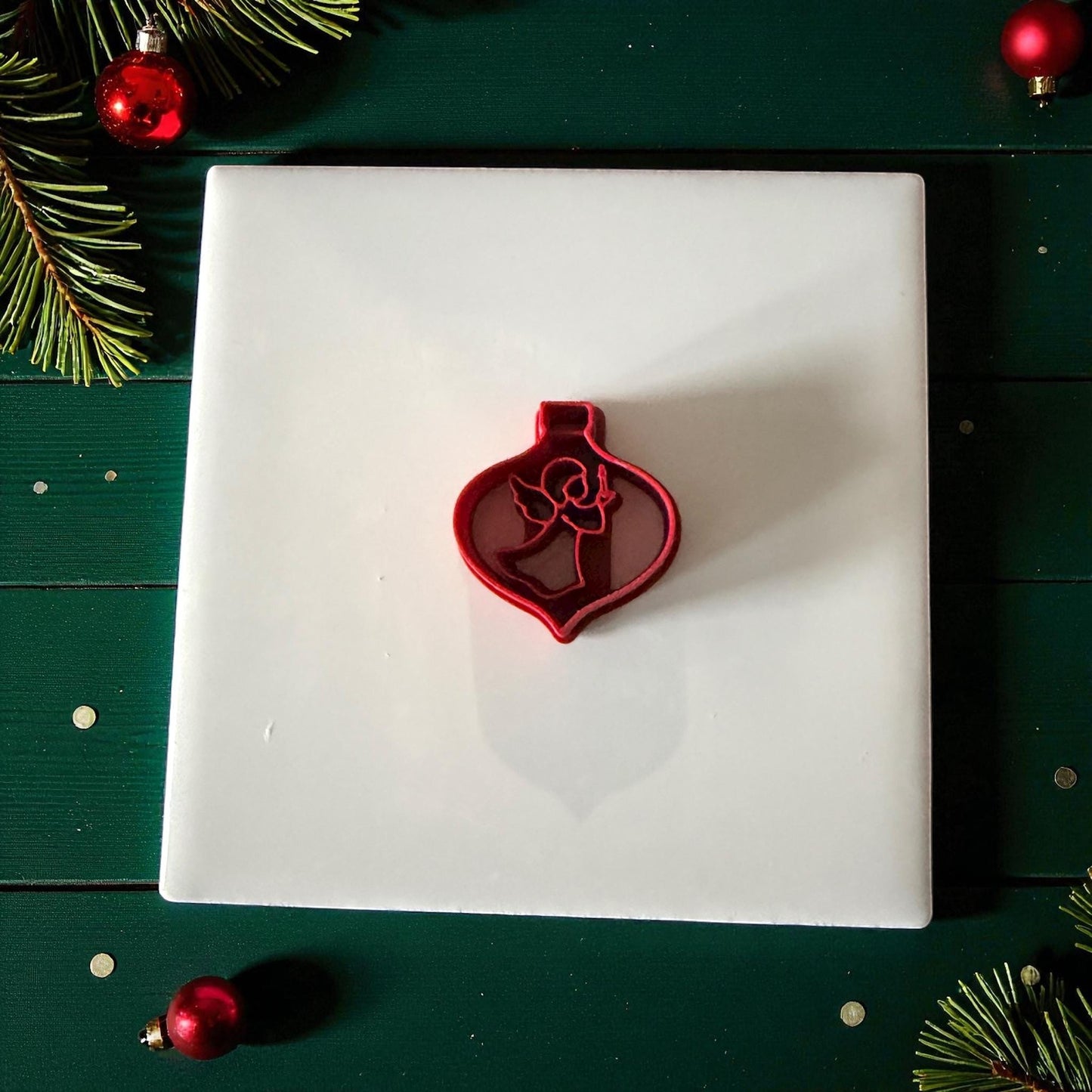 Angel ornament cutter centered on white tile with green holiday background