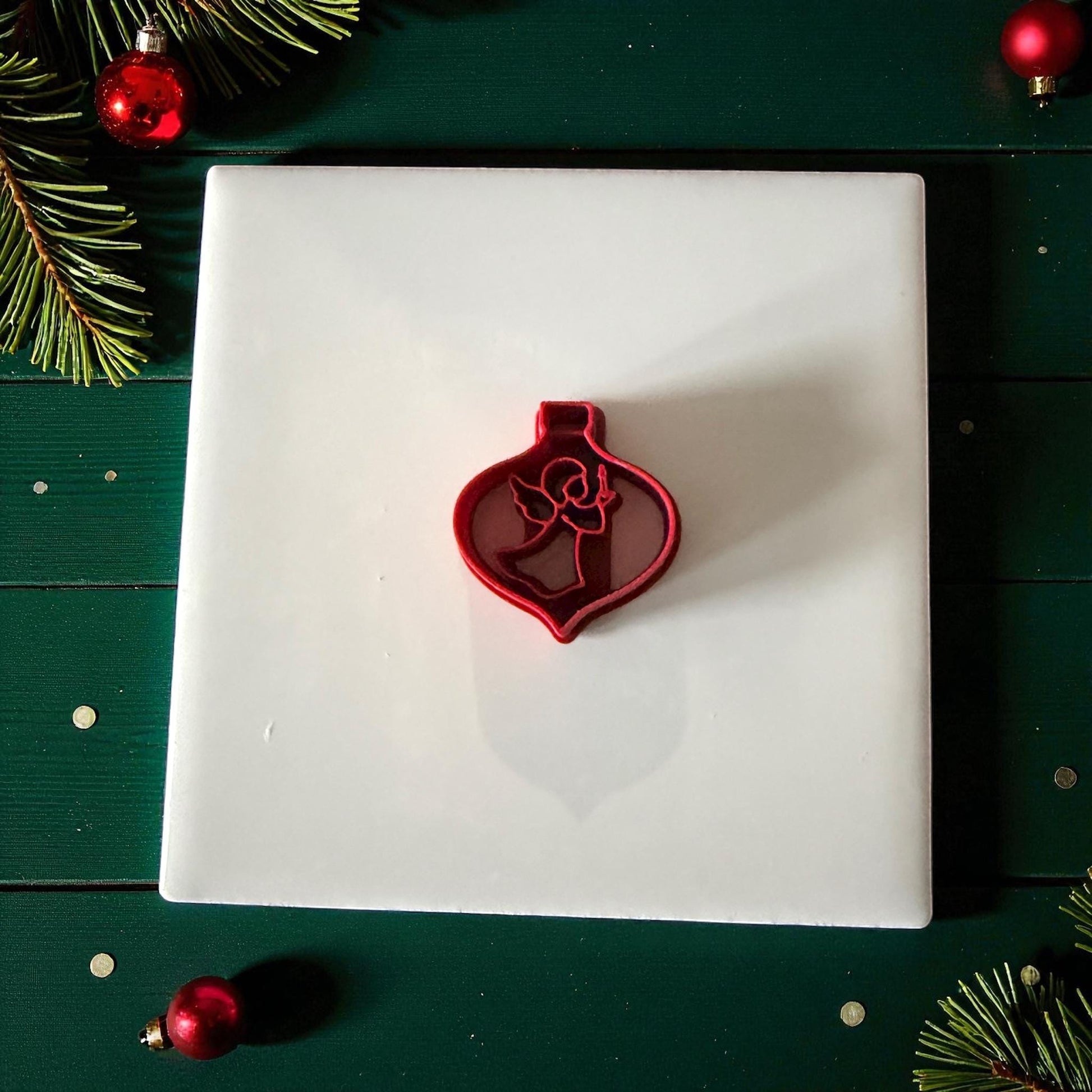 Angel ornament cutter centered on white tile with green holiday background