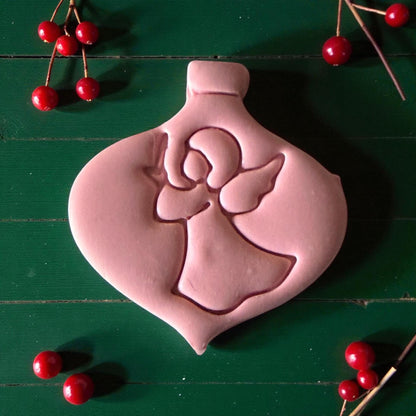 Close-up of pink angel ornament clay imprint with berries and pine sprigs