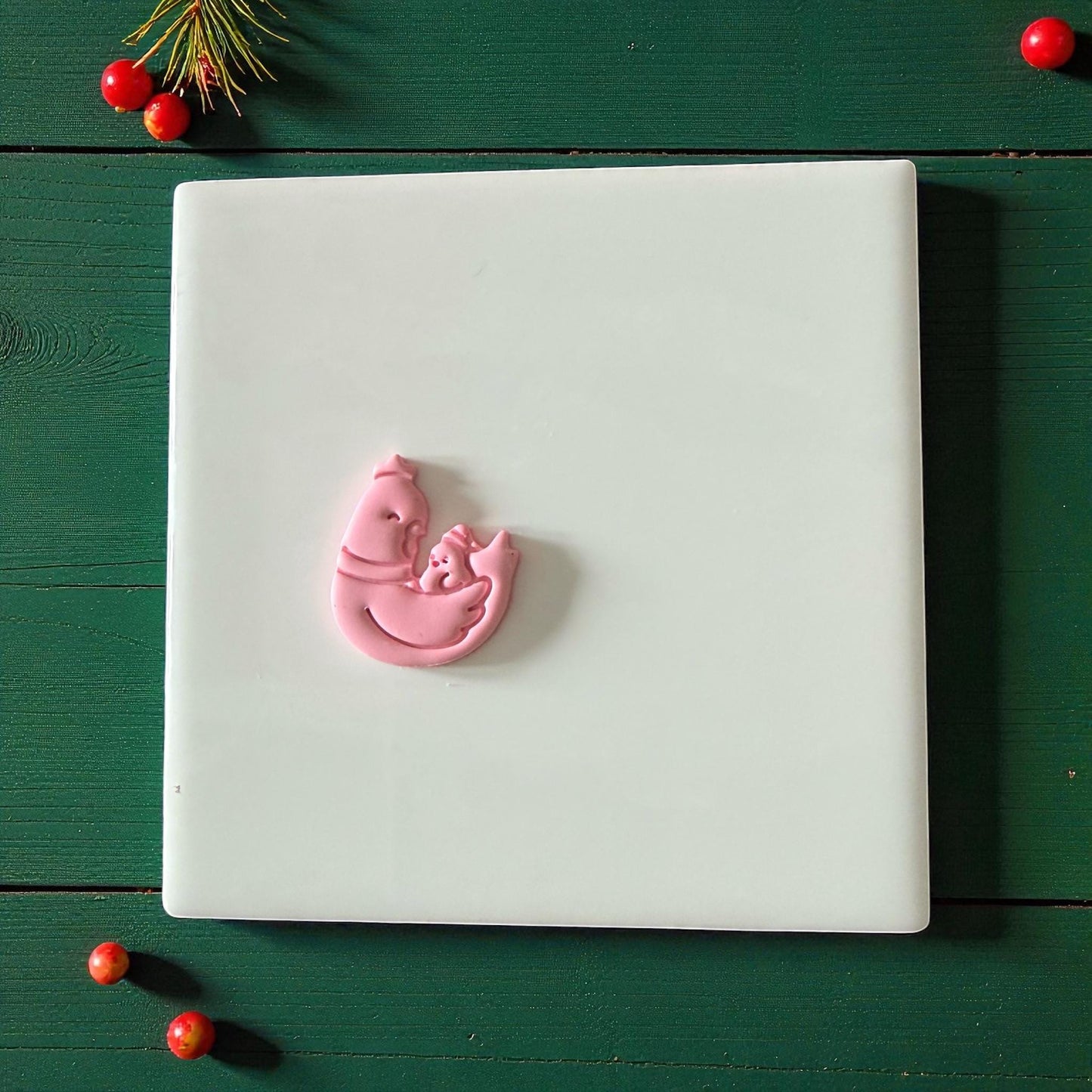 Pink chicken and chick clay imprint centered on white tile with festive background