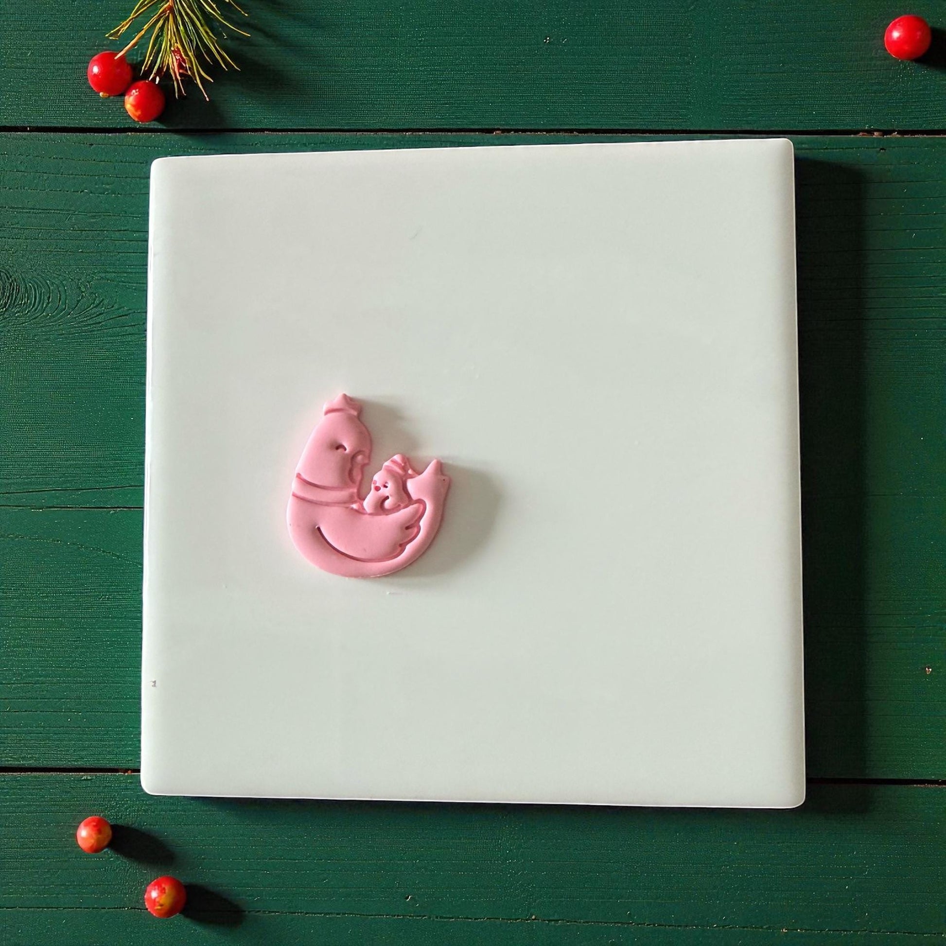 Pink chicken and chick clay imprint centered on white tile with festive background