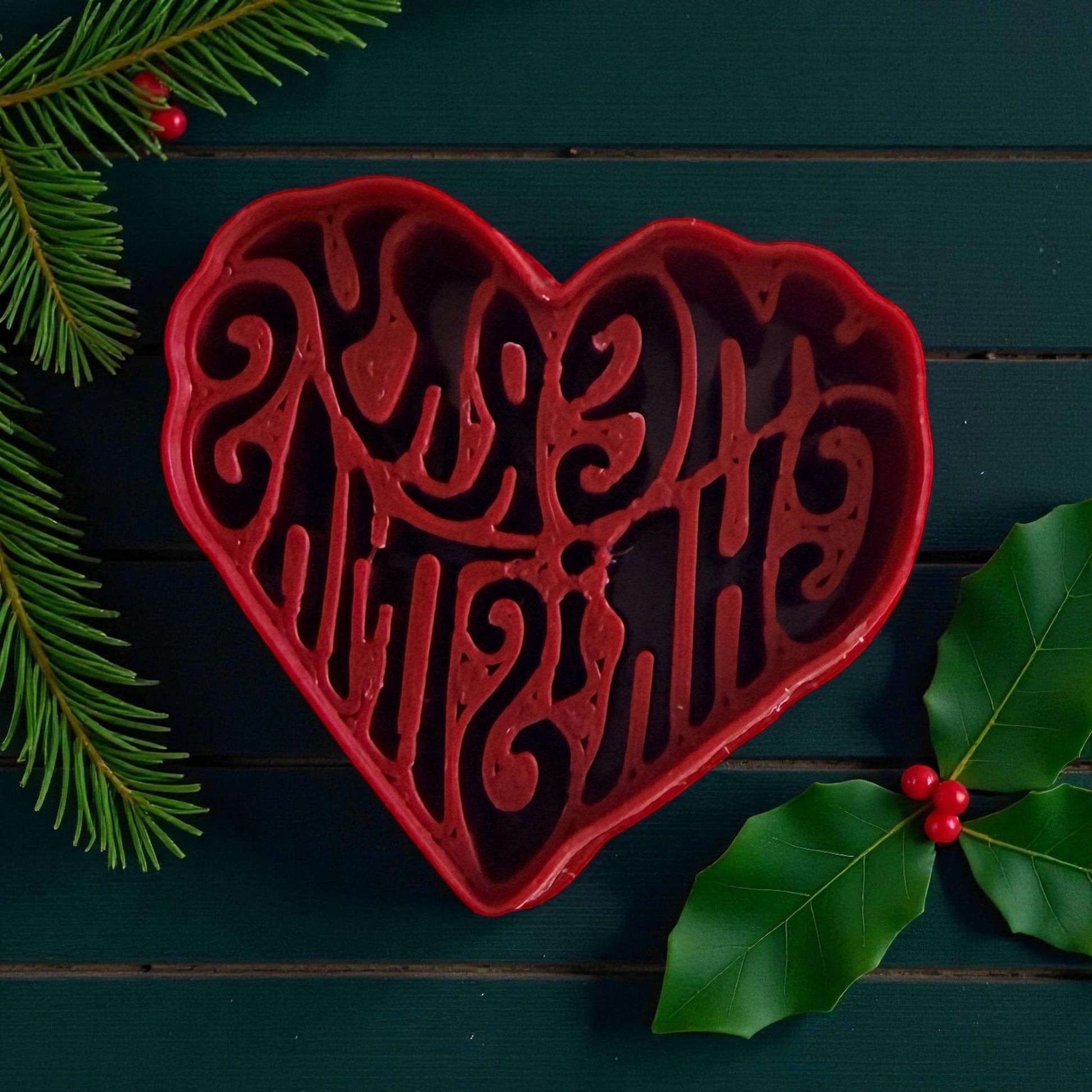 Red heart-shaped polymer clay cutter with Merry Christmas text and holly leaves