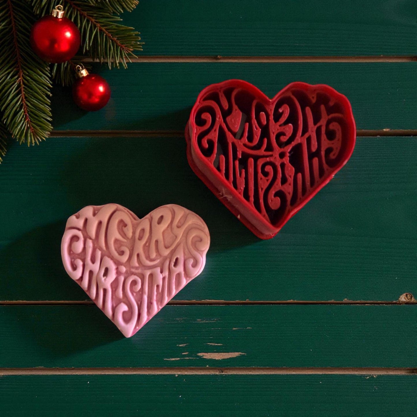 Red heart cutter and pink clay heart with Christmas design on green background
