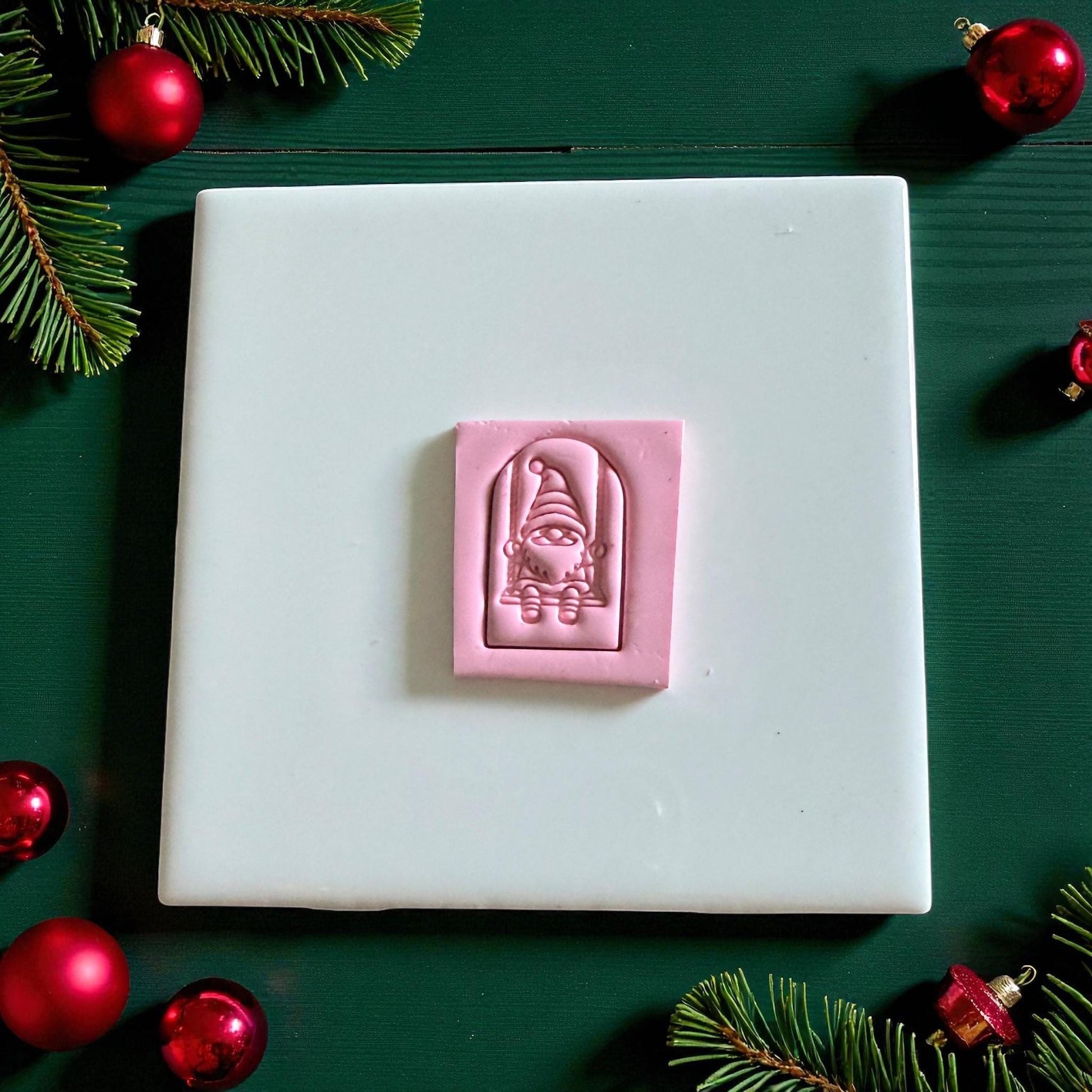 Pink clay rectangle embossed with gnome on swing inside arched frame