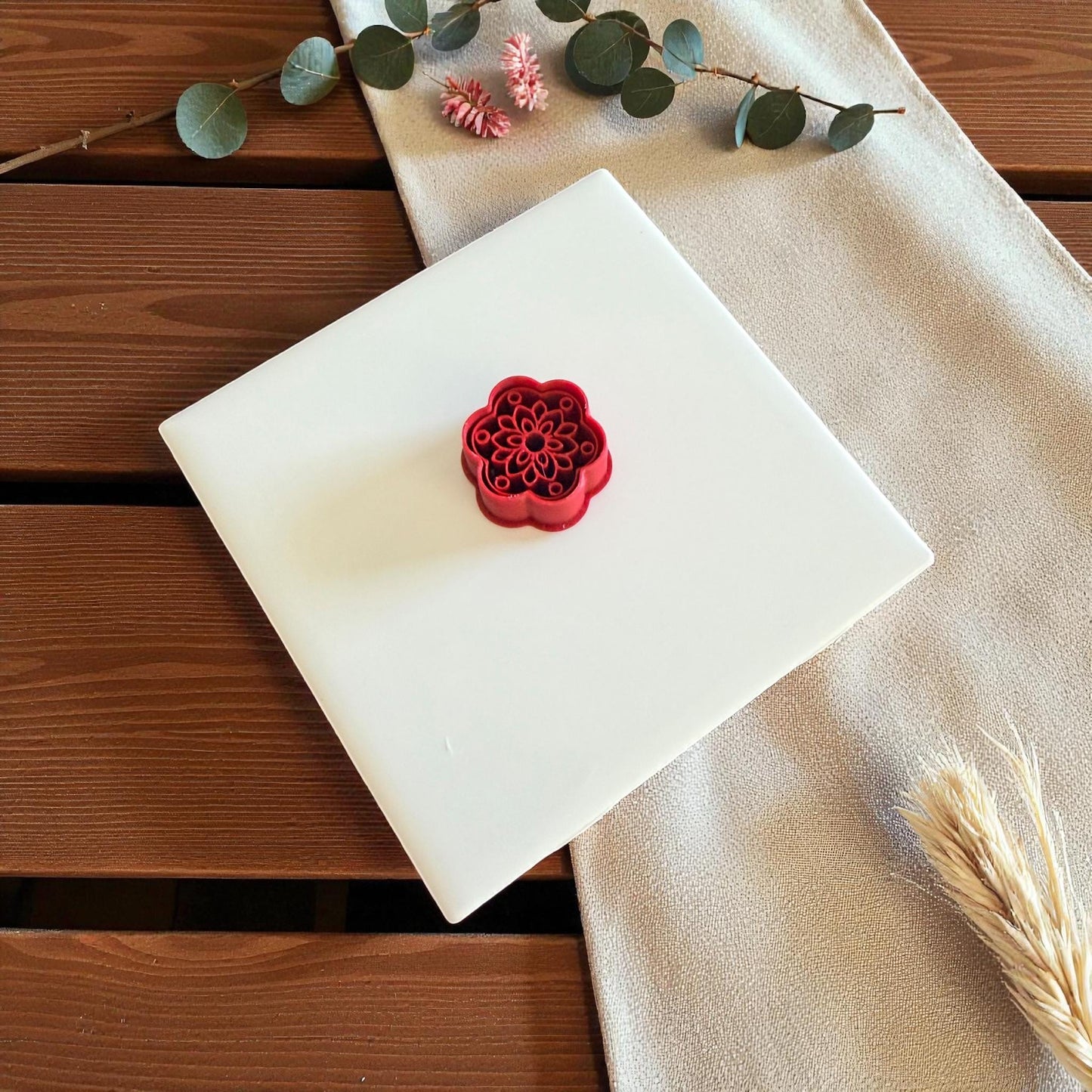 Red cutter on white tile with beige cloth and dried wheat stems