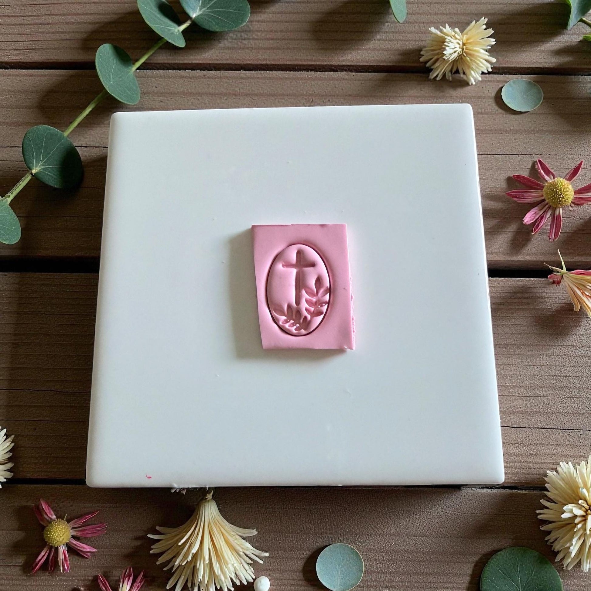 Pink clay with oval cross and olive branch impression on white tile
