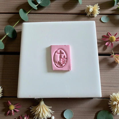 Pink clay with oval cross and olive branch impression on white tile