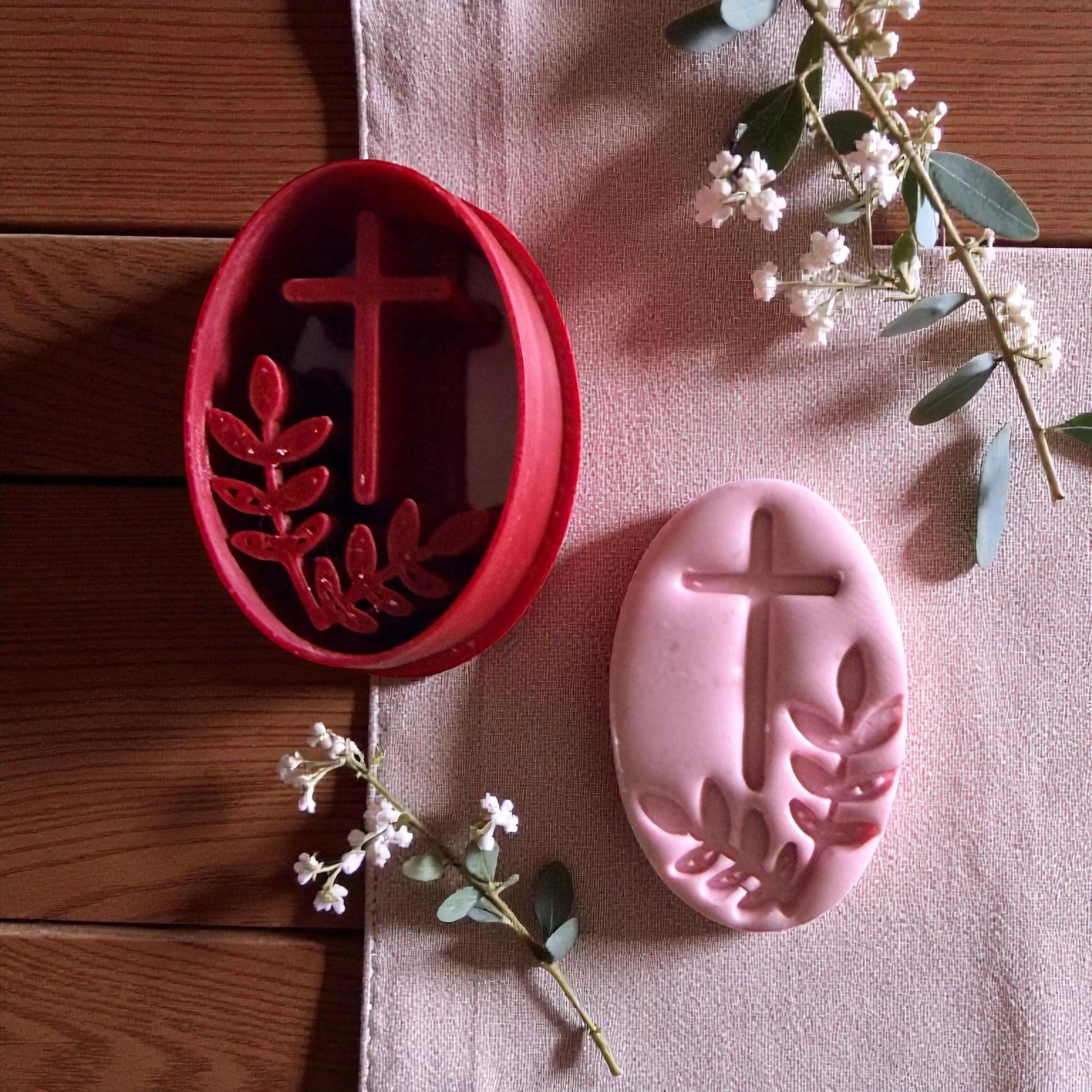 Red cutter and pink oval clay side by side with greenery and fabric