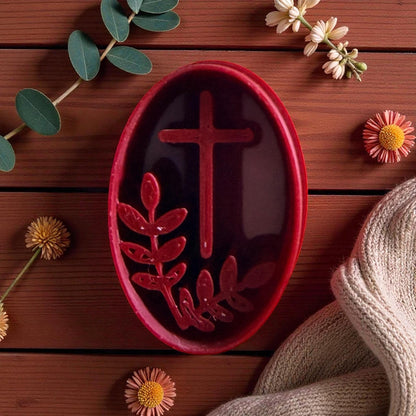 Red oval clay cutter with cross and branch on white tile surrounded by flowers