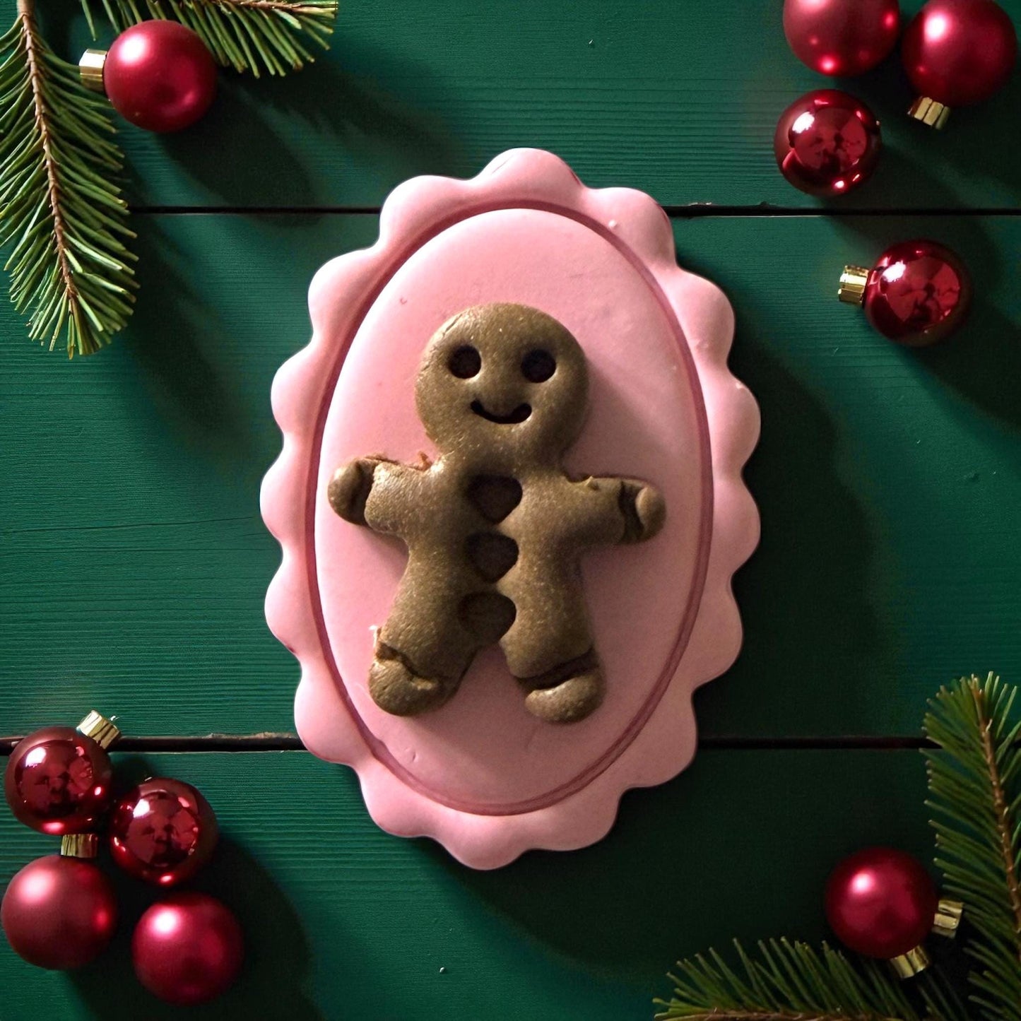 Close-up of pink cameo clay piece with green gingerbread on green wood background