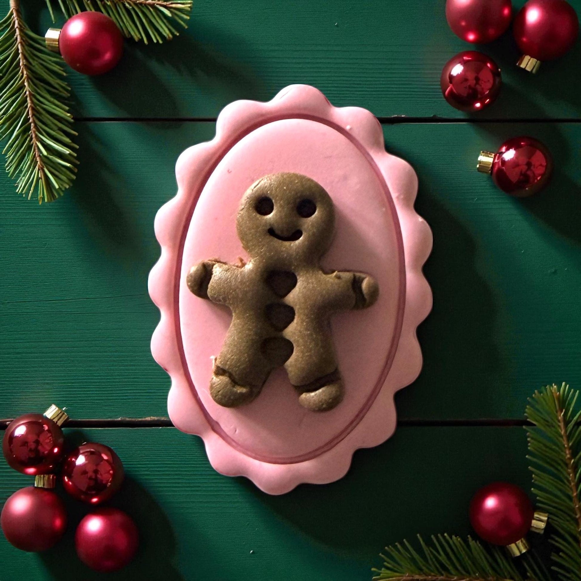 Close-up of pink cameo clay piece with green gingerbread on green wood background
