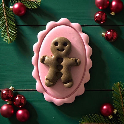 Close-up of pink cameo clay piece with green gingerbread on green wood background