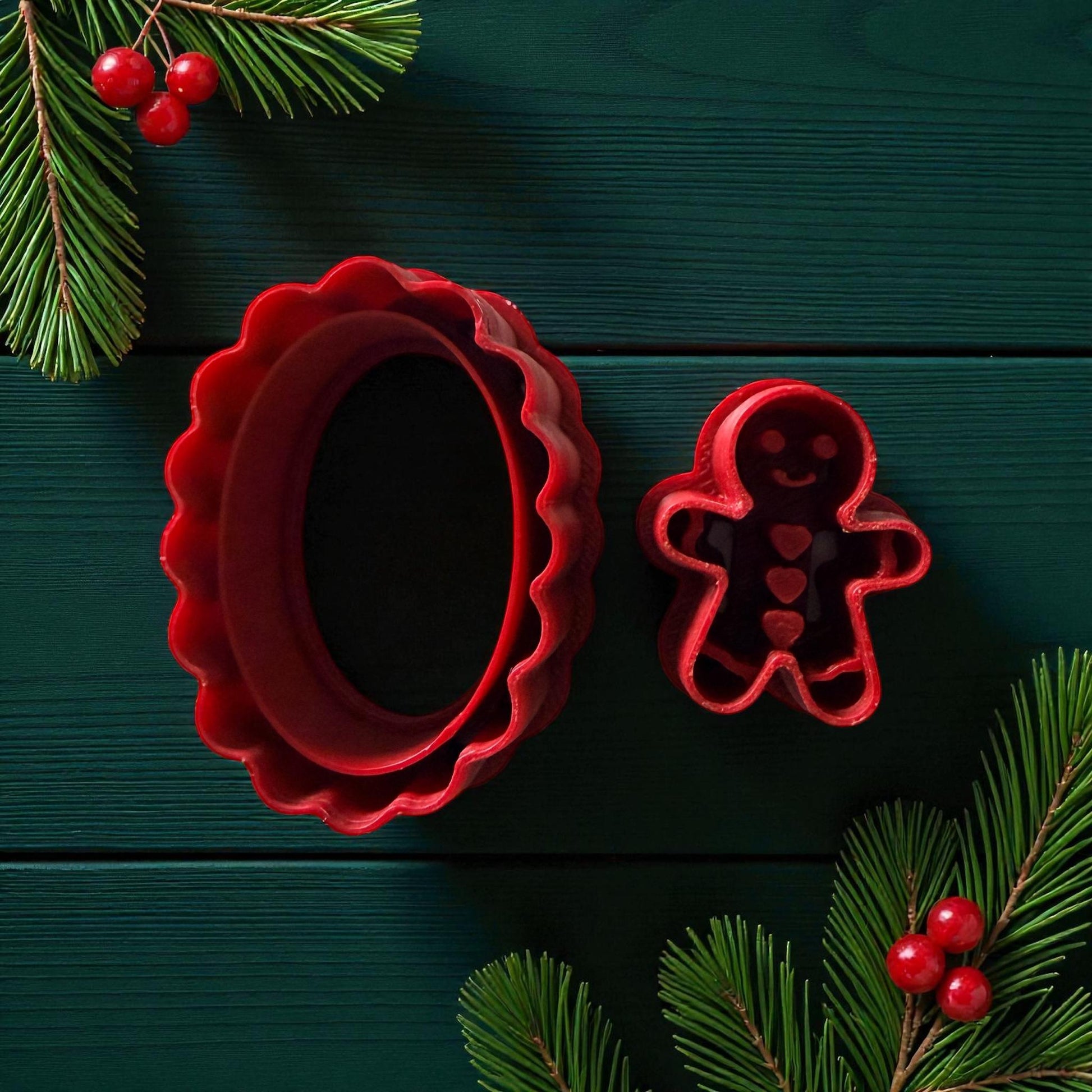 Red oval scalloped cutter and gingerbread cutter on dark green background with pine branches