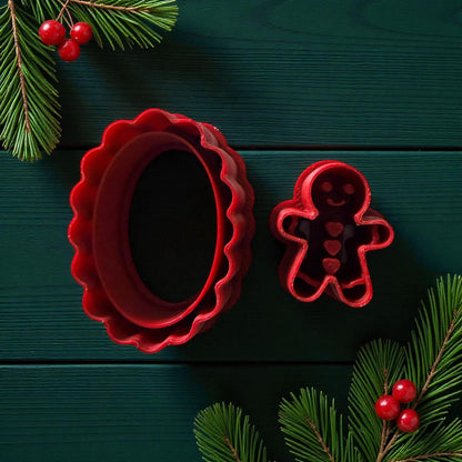 Red oval scalloped cutter and gingerbread cutter on dark green background with pine branches