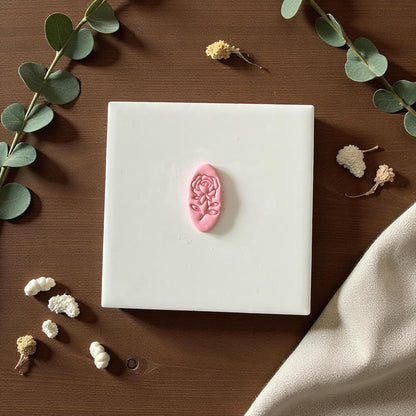 Oval rose clay imprint centered on white tile with scattered flowers and neutral background