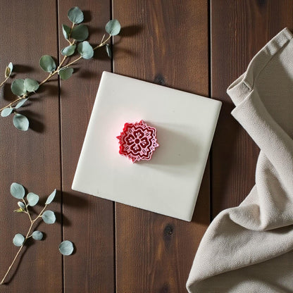 Boho mandala clay cutter centered on white tile with beige cloth and eucalyptus