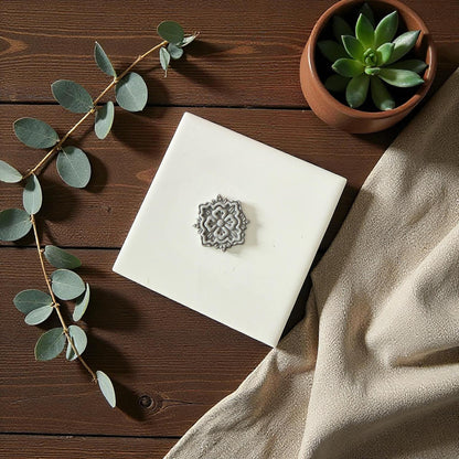 Gray mandala clay imprint on white tile with succulent and neutral background