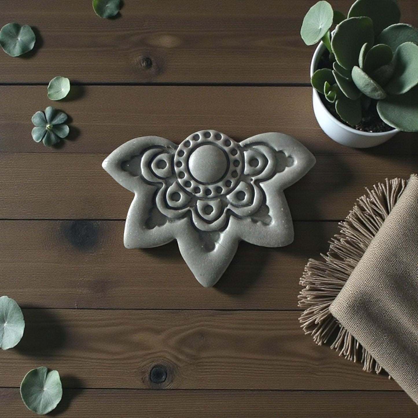 Gray mandala lotus clay imprint on wood background with succulent and fabric