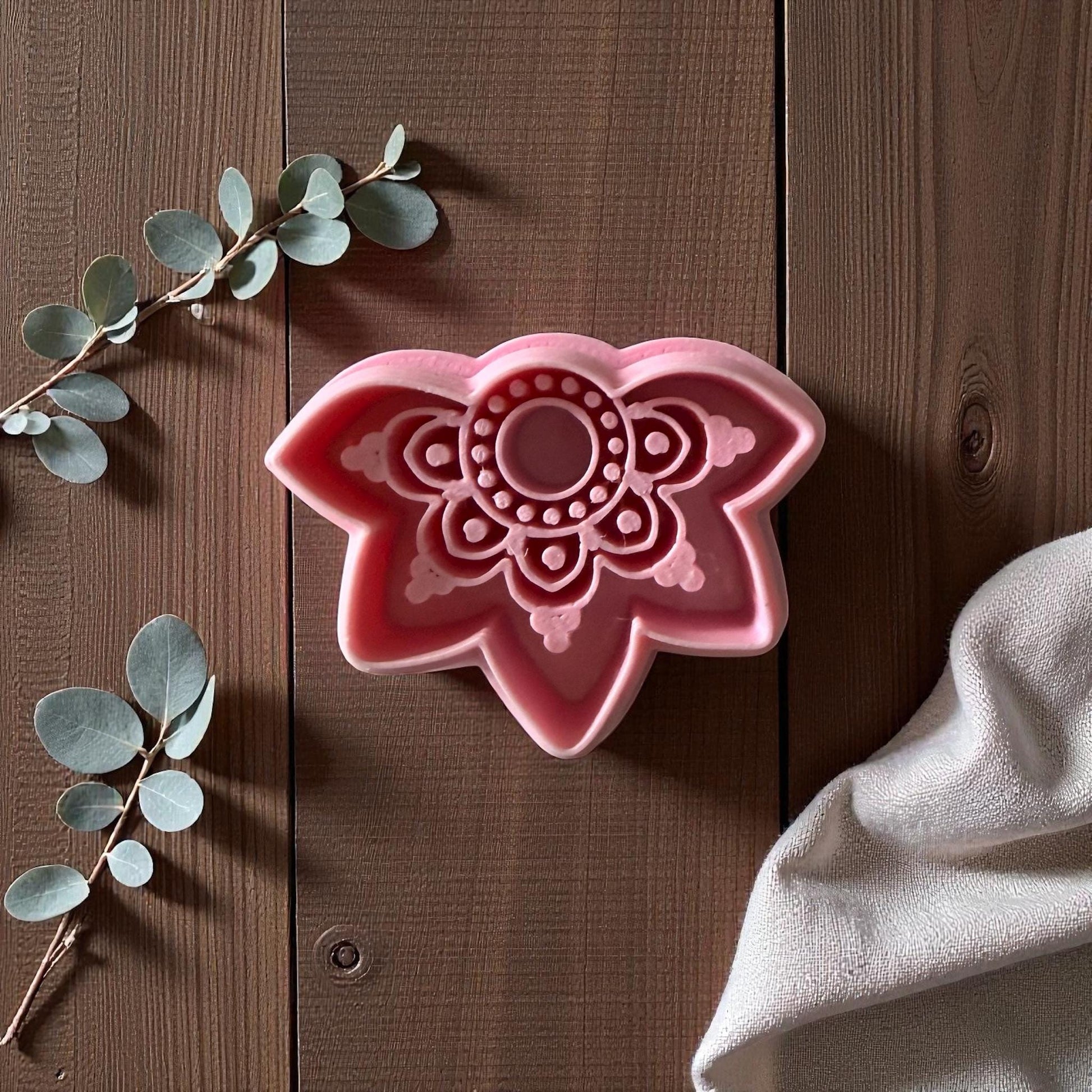 Pink boho lotus polymer clay cutter on wooden surface with eucalyptus