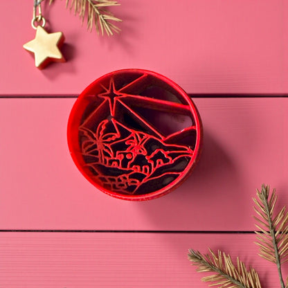 Red Bethlehem clay cutter on pink wood background with pine and star decor