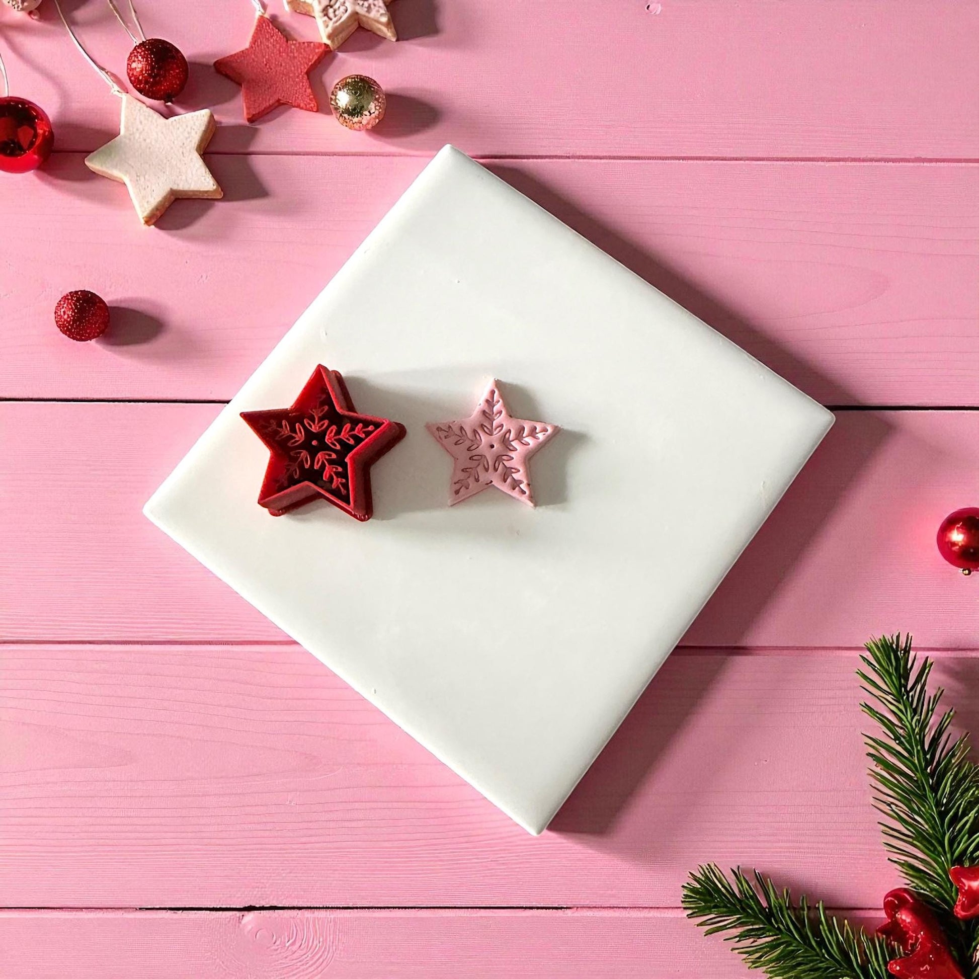 Red and pink Scandinavian star clay cutters on white tile with holiday decor