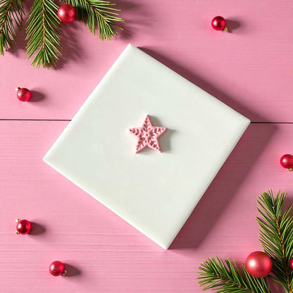 Small Scandinavian star clay imprint on white tile surrounded by red ornaments