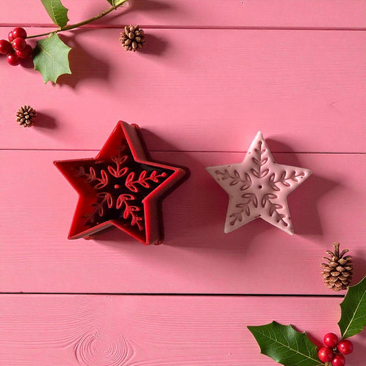 Nordic folk star clay cutter and imprint on pink background with pinecones
