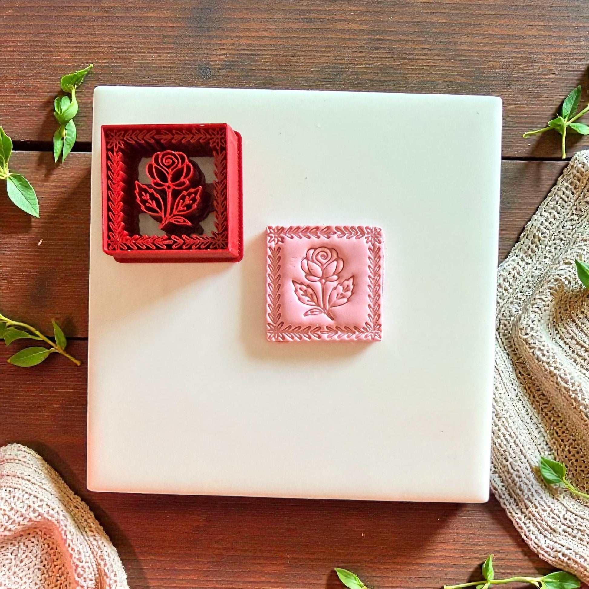 Red and pink rose frame cutters on tile with fabric and leaves