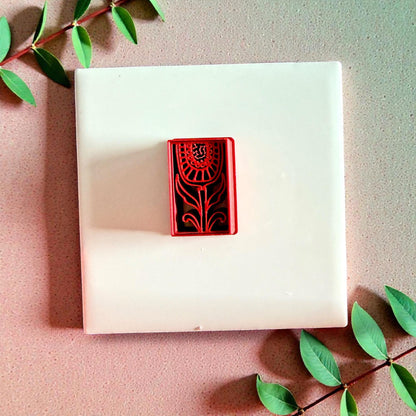 Red rectangular floral cutter centered on white tile with greenery
