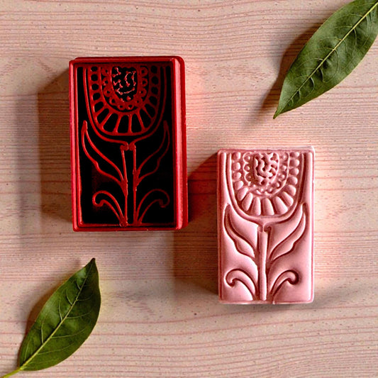 Pink clay and red cutter floral pair with leaves on wood surface