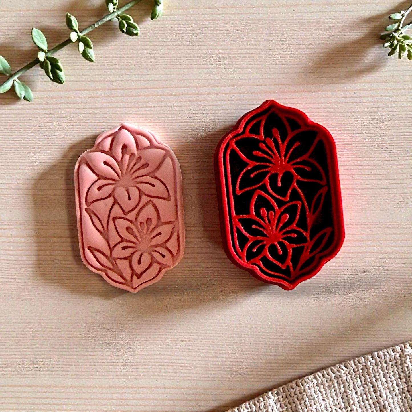 Red lily cutter and pink floral clay impression on wood background