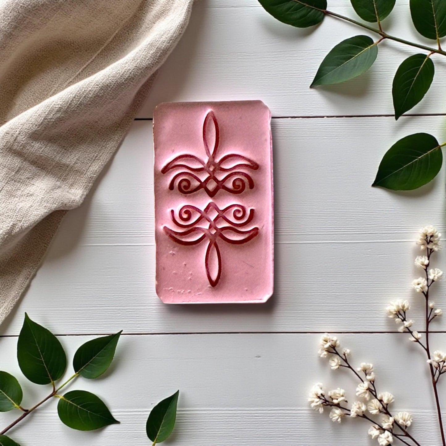 Close-up of pink clay impression featuring bootstitch scroll design