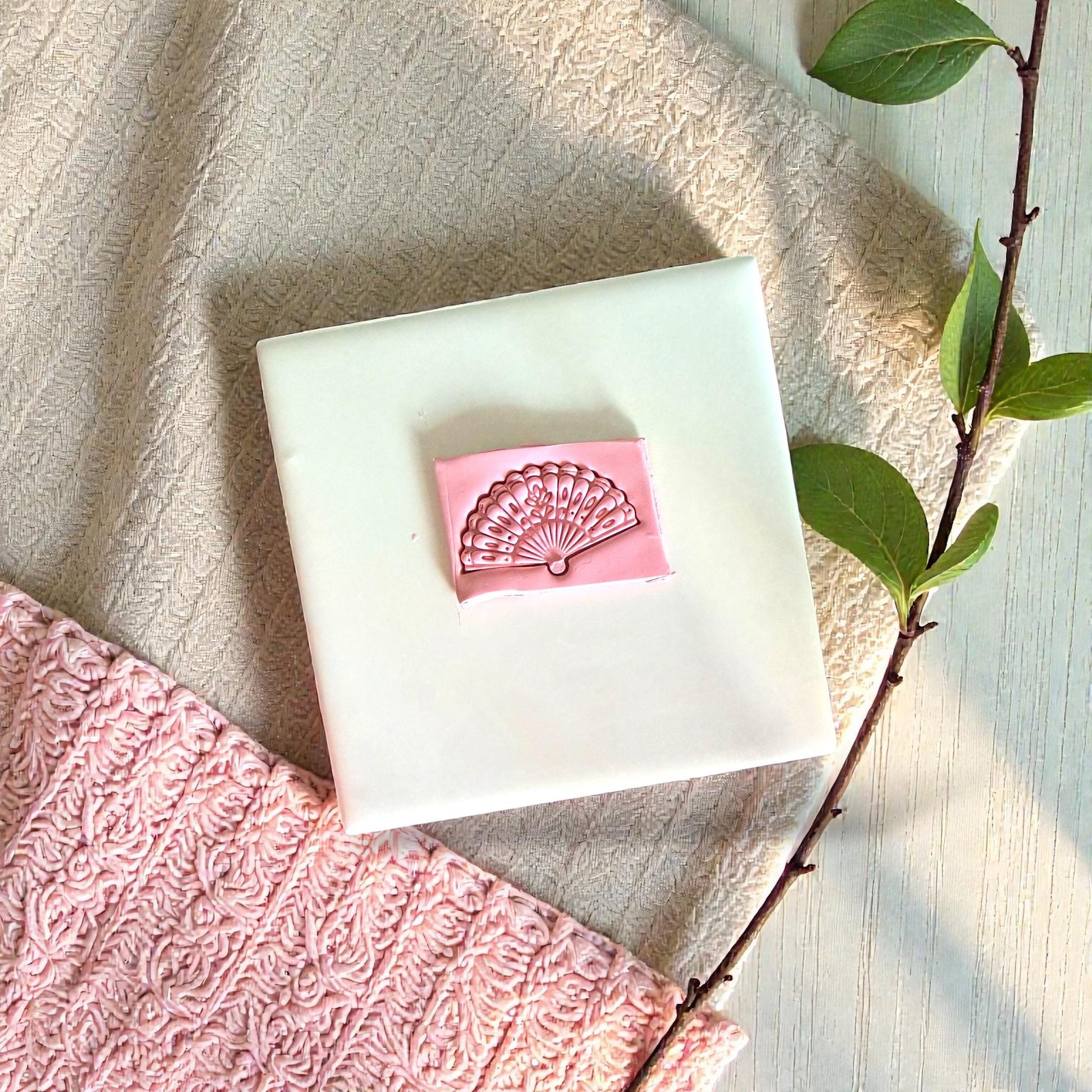 Pink clay fan pressed into tile with pink and green fabrics