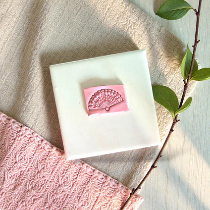 Pink clay fan pressed into tile with pink and green fabrics