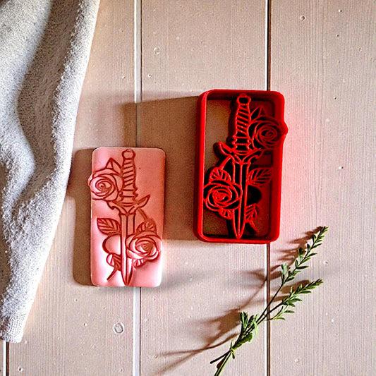 Red sword and rose cutter with pink clay impression on beige wood background